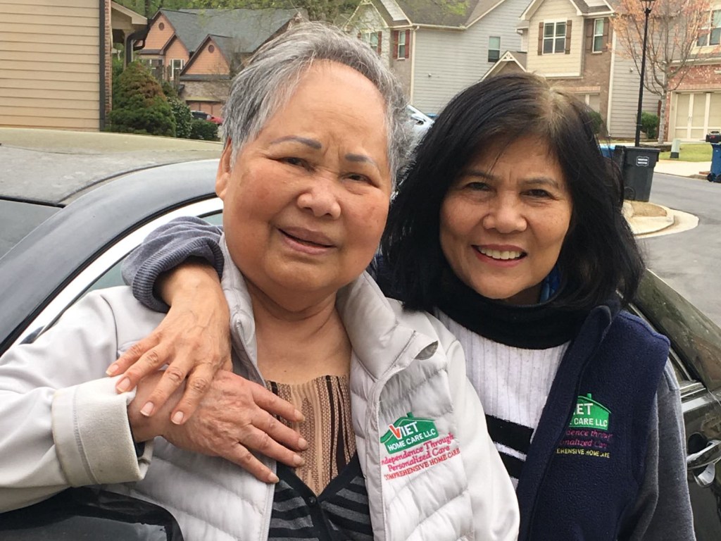 Thao Tran of Viet Home Care poses in front of her car with a Vietnamese senior who she drives around Norcross, Georgia.