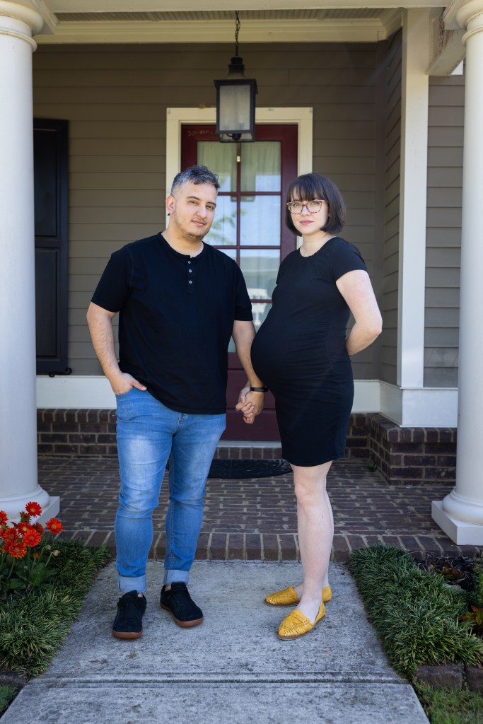 Jorge and Joanie Santander, who live on the left and more affluent side of Buford Highway in Norcross, Georgia, pose in front of Joanie's parents' home.