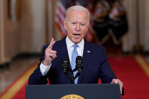 President Joe Biden stands behind a podium with a microphone to give a speech.