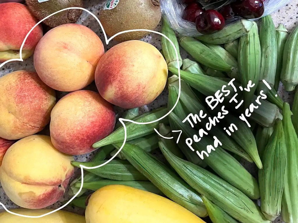 An overhead shot of peaches, kiwis, apples, cherries, okra, and yellow squash.