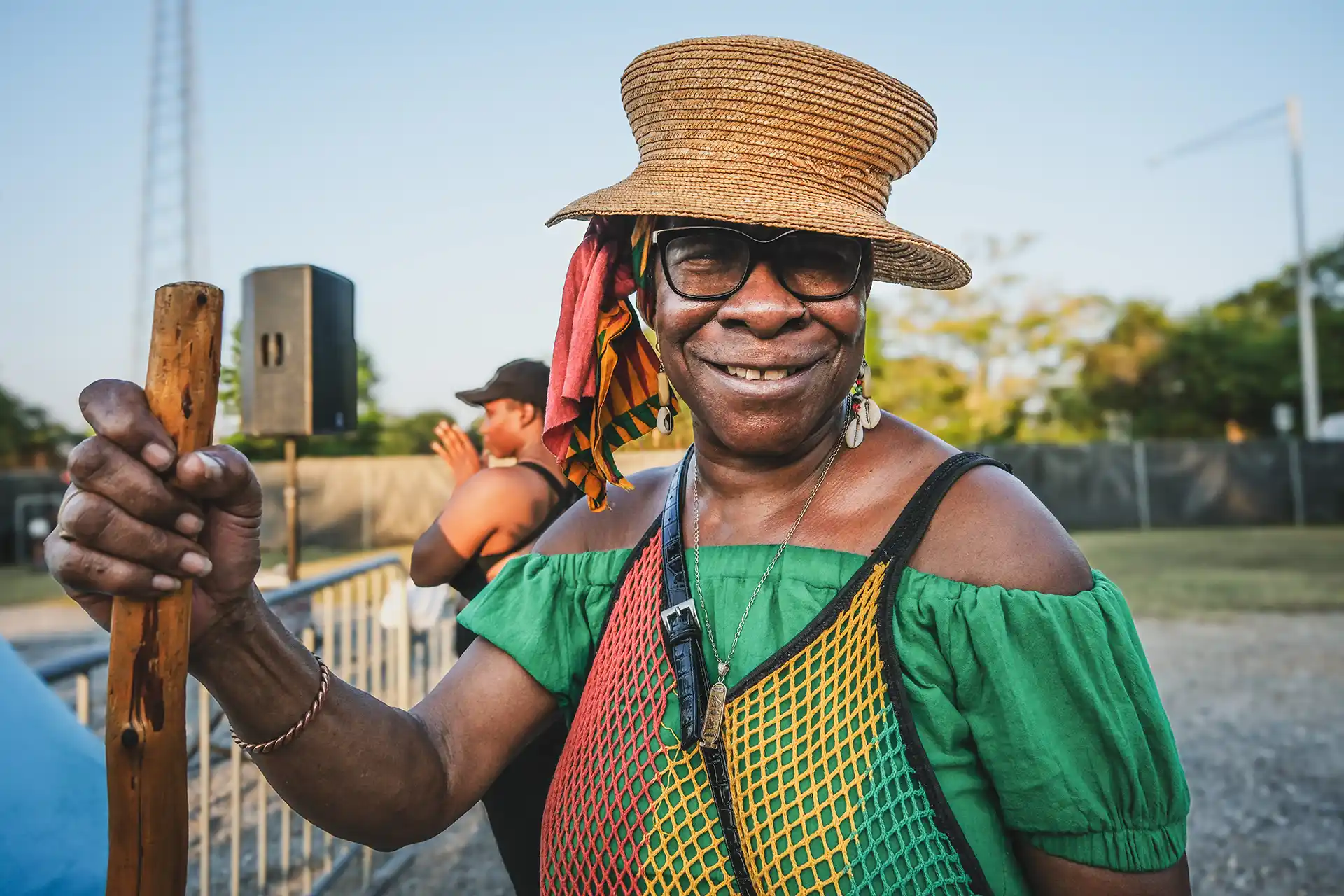 A smiling woman holds a wooden staff.