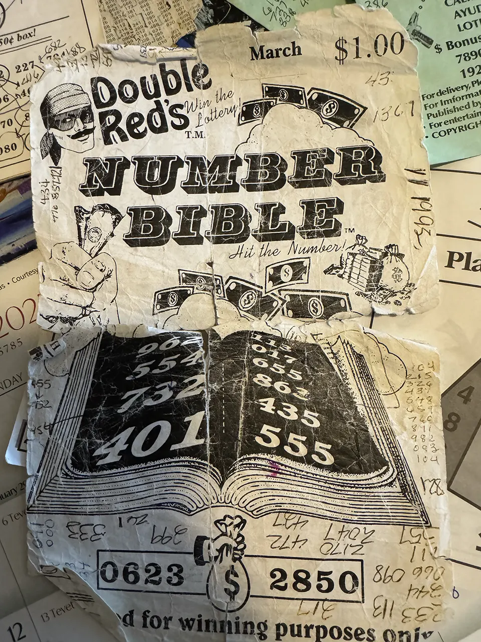 A tattered book cover reading, "Double Red's Number Bible" lays on a stack of papers.